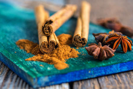Ceylon cinnamon (sticks and powder) and star anise on a wooden board.の写真素材