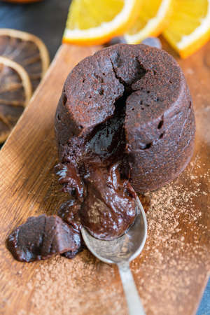 Cupcake with liquid chocolate filling on a wooden plate.の写真素材