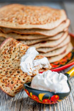 Pancakes with sour cream on a wooden table closeup.