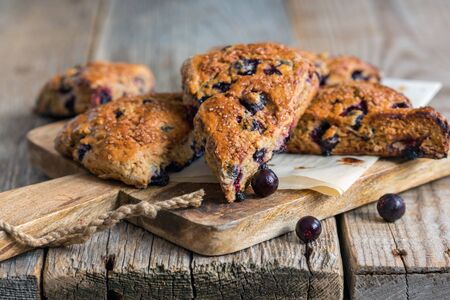 Homemade scones flavored with black currants on a wooden table.の写真素材