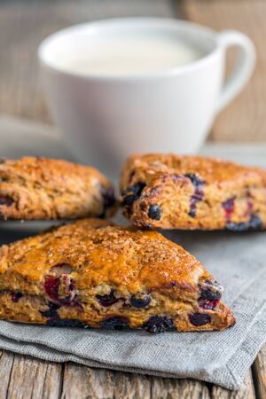 Scones with black currant on a linen napkin and cup of milk.の写真素材