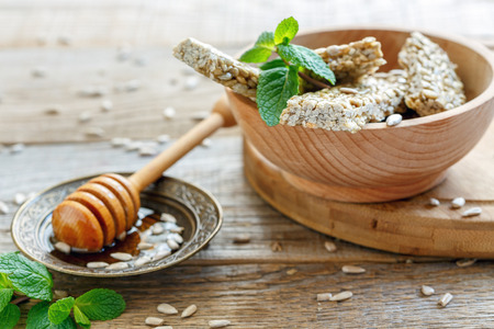Bowl with a bars of sunflower seeds in honey on the old wooden table.の写真素材