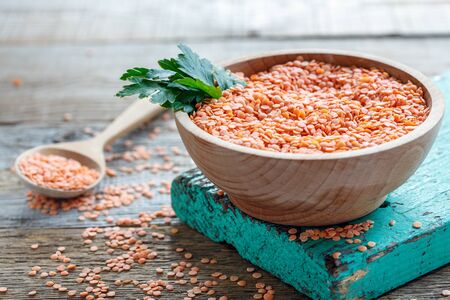 Bowl with red lentils and parsley on an old wooden table.の写真素材