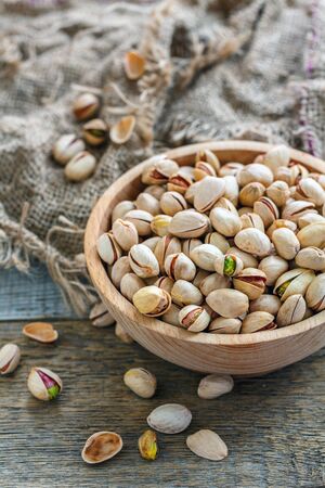 Raw pistachios in bowl on an old rustic table.の写真素材