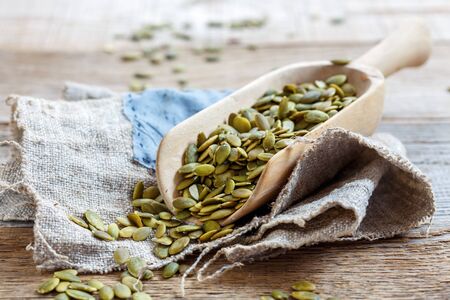 Wooden scoop with pumpkin seeds on an old burlap.の写真素材