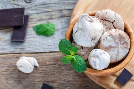 Chocolate meringue and mint green in a wooden bowl on old table.の写真素材