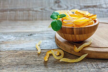 Bowl with mint and candied orange on old wooden table.の写真素材