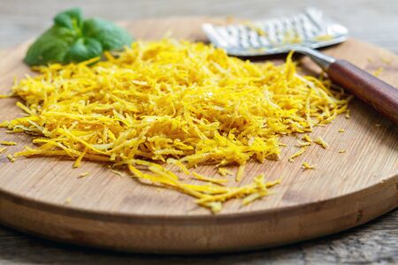 Lemon zest grated and mint on a wooden cutting board.の写真素材