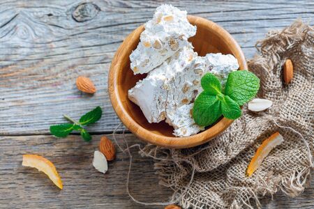 Nougat with candied orange and almonds in a bowl on old wooden table.の写真素材