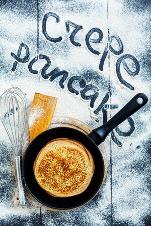 Frying pan with pancakes on a dark background sprinkled with white flour.の写真素材