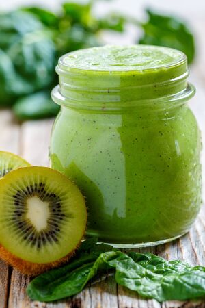 Green smoothie in jar of spinach and kiwi on an old wooden table close up.の写真素材
