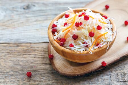 Bowl with sauerkraut and cranberry on an old wooden table.の写真素材