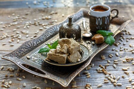 Halva on a tray and a cup of coffee on old table near the window.の写真素材