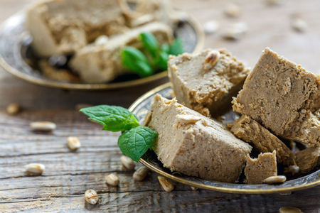 Halva from sunflower seeds and fresh mint on a wooden table close-up, selective focus.