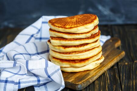 Pancake stack and kitchen towel on the old wooden table.