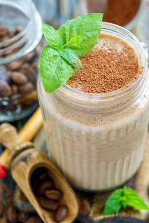 Coffee smoothie with banana and yogurt in a glass jar on a wooden table.の写真素材
