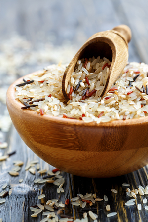Bowl with red, white, brown and wild rice on a wooden table, selective focus.の写真素材