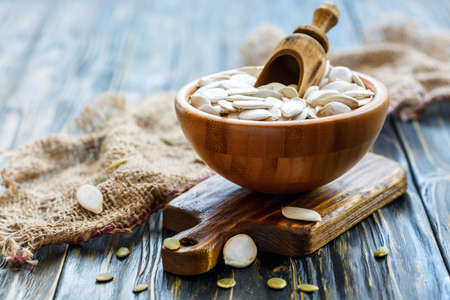 Bowl with pumpkin seeds and a scoop on the old wooden table, selective focus.の写真素材