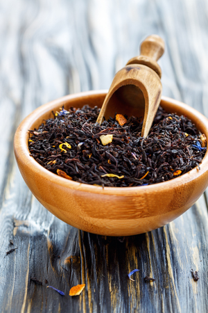 Black tea with bergamot and a scoop in a bowl on wooden table, selective focus.の写真素材