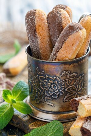 Vanilla cookies Savoiardi with chocolate in a metal cup on a wooden table.の写真素材