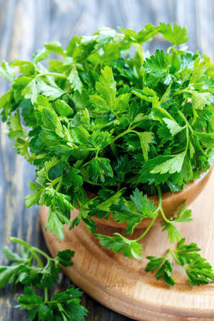 Parsley leaves in drops of water in a bowl on a wooden stand, selective focus.の写真素材