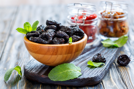Prunes in a bowl on wooden table, selective focus.の写真素材
