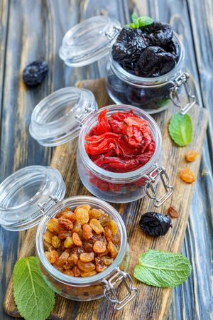 Dried fruit in glass jars on wooden table, selective focus.の写真素材