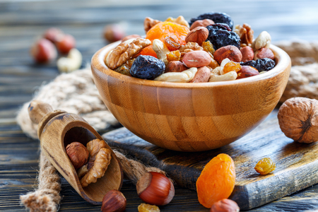 Bowl of nuts and dried fruits and wooden scoop on the old table.の写真素材