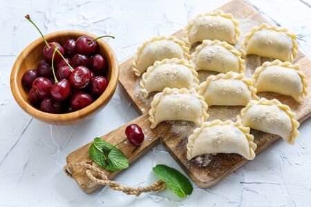 Board with dumplings with cherries on the old white table, selective focus.の写真素材