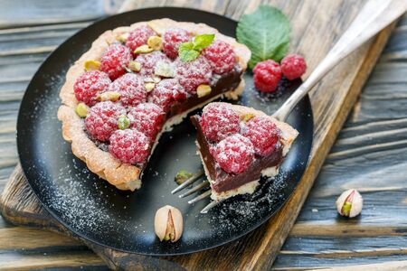 Tartlet with chocolate and raspberries on a black plate, selective focus.の写真素材