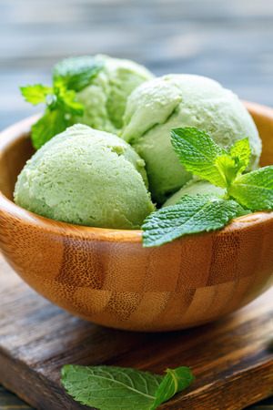 Homemade mint ice cream in a wooden bowl on old table, selective focus.の写真素材