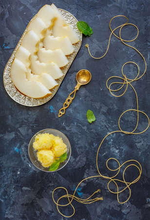 Melon sorbet and a dish with melon slices on a dark stone background.の写真素材
