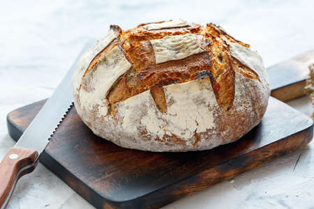 Vermont homemade bread on an old wooden board and a bread knife.