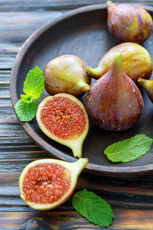 Dish of sliced ripe figs on wooden table, selective focus.