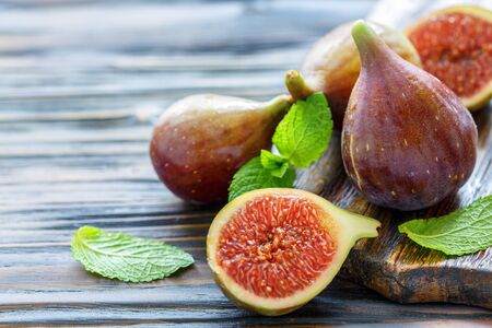 Half ripe sweet figs and whole fruits on the old wooden table, selective focus.