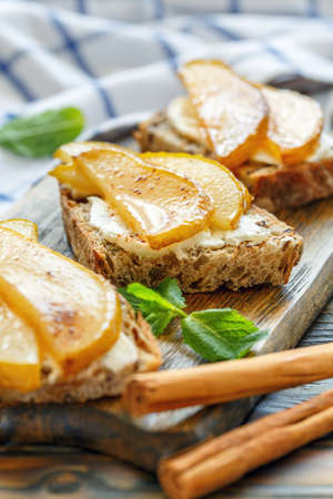 Homemade bread with ricotta and caramelized pears on a wooden stand, selective focus.の写真素材