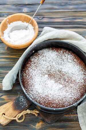 Chocolate cake dusted with powdered sugar in a metal form, selective focus.の写真素材