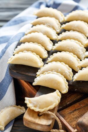 Homemade dumplings with cottage cheese for cooking on the old kitchen table, selective focus.の写真素材