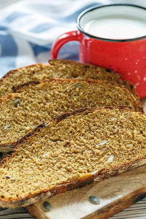 Mug with milk and slices of homemade pumpkin bread on the kitchen table, selective focus.