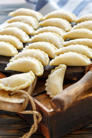 Homemade dumplings with cottage cheese on wooden Board, selective focus.