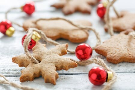 Christmas garland from gingerbread and red balls on white wooden table, selective focus.の写真素材