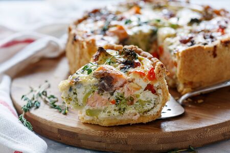 Piece of quiche with salmon and broccoli closeup, selective focus.