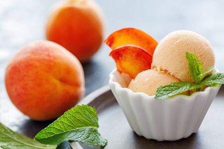 Homemade peach ice cream and mint in bowl on wooden plate, selective focus.の写真素材
