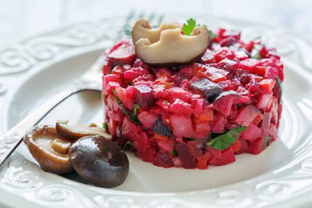 Russian salad with marinated mushrooms on a white plate closeup selective focus.の写真素材