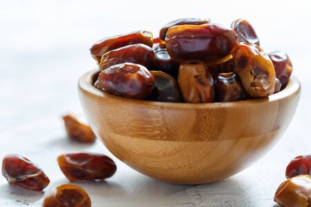 Dried dates in a wooden bowl closeup on white table,selective focus.の写真素材