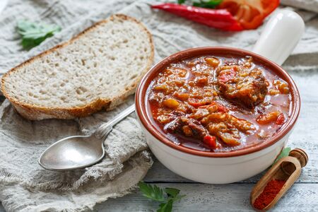 Goulash with meat, potatoes, hot pepper and paprika in a bowl on a wooden table, selective focus.の写真素材