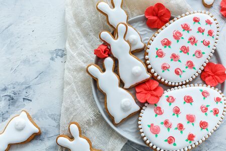 Glazed Easter cookies and red sugar flowers on an old white table.の写真素材