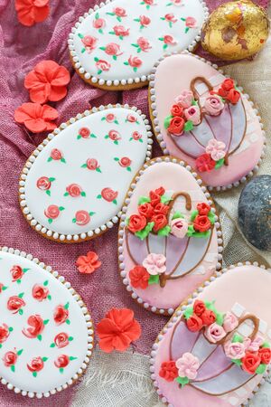 Glased Easter cookies with floral decoration on a textile background.