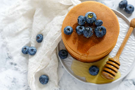 Plate of pancakes with blueberry and honey on a white table, selective focus.の写真素材