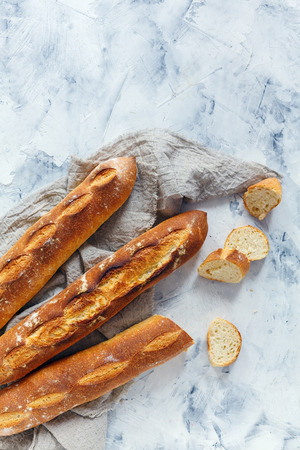 Artisanal baguettes and sliced baguette and linen cloth on white concrete background.の写真素材
